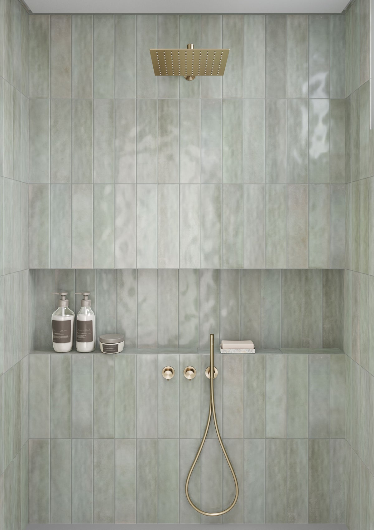 Modern bathroom shower area with tiled walls, gold fixtures, and toiletries.