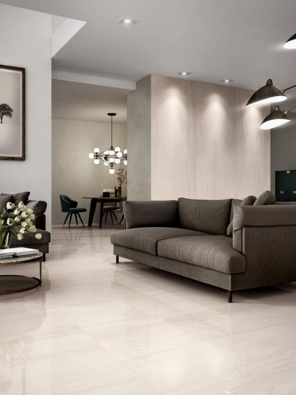 Modern living room with a gray sofa, dining area in the background, and large porcelain panels for a seamless look.