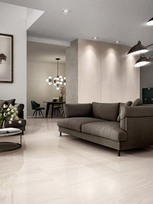 Modern living room with a gray sofa, dining area in the background, and large porcelain panels for a seamless look.