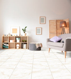 A bright, modern living room featuring large, light beige marble-look floor tiles. The room is styled with a gray sofa, a wooden shelving unit, a gray pouf, and a floor lamp.