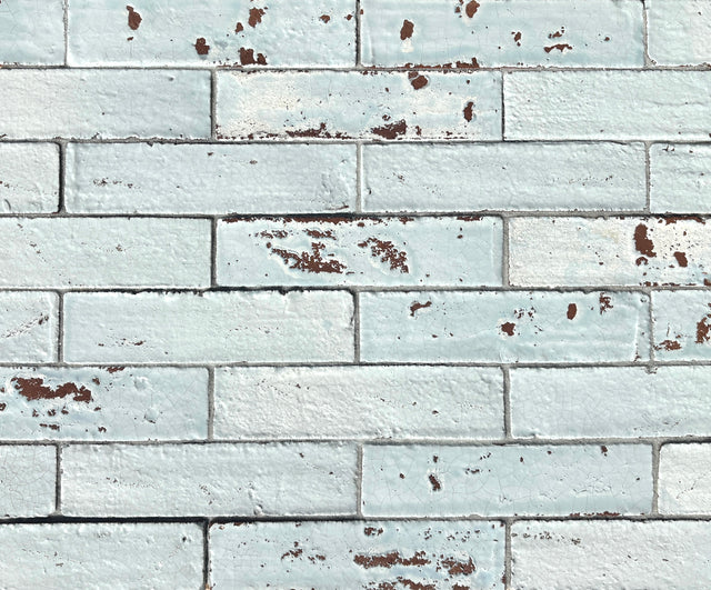 Artesano Cozumel Blue Glossy Brick 2x9 clay tile in a running-bond layout, pale blue crackle glaze with chipped red clay edges